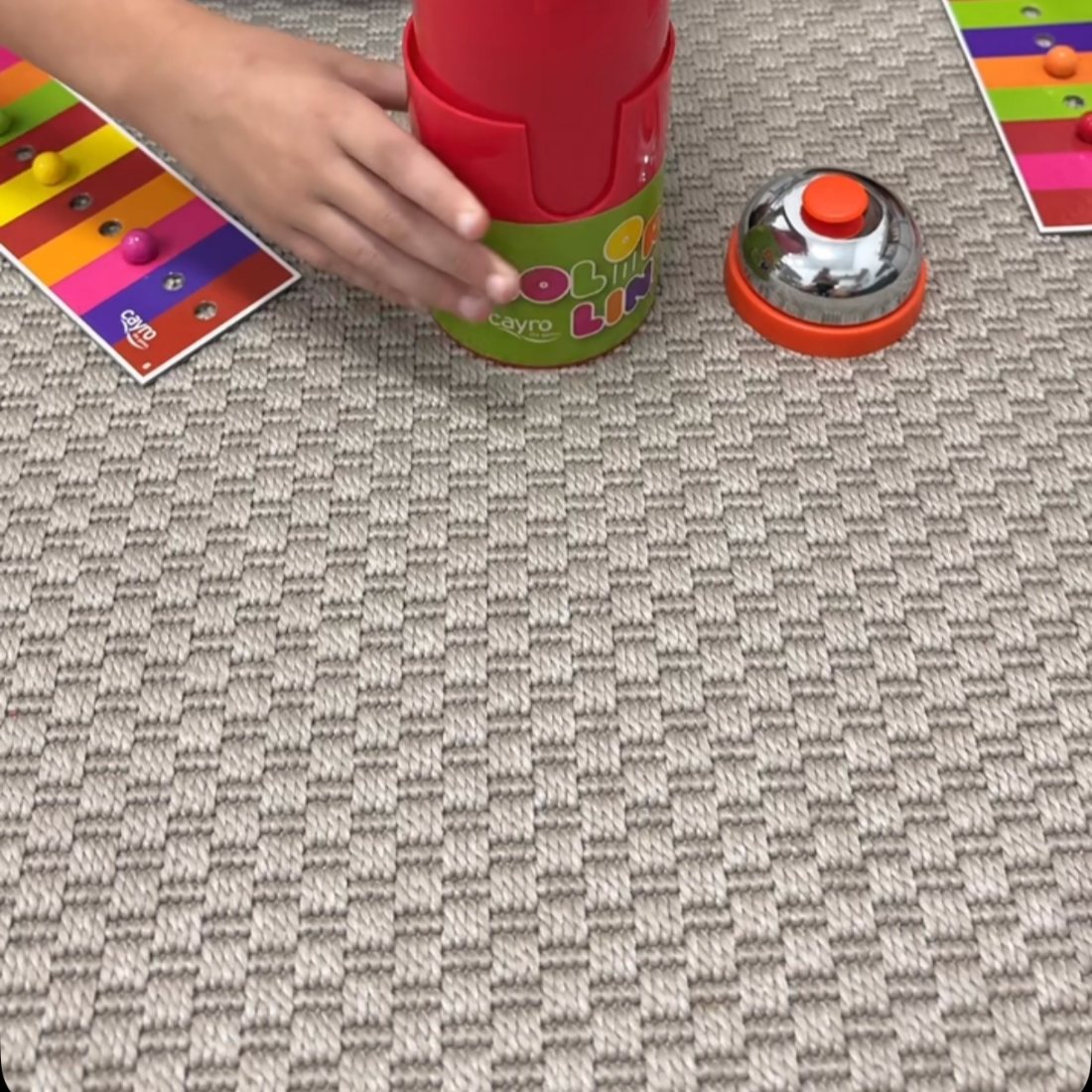 Las manos de un niño jugando con un juego de mesa en el suelo